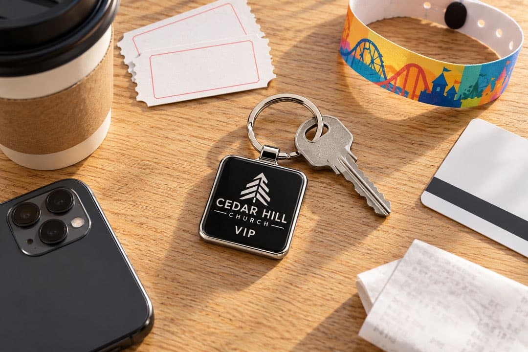 A Cedar Hill Church key tag on a keyring, next to movie tickets, a theme-park wristband, a hotel key card and a coffee.